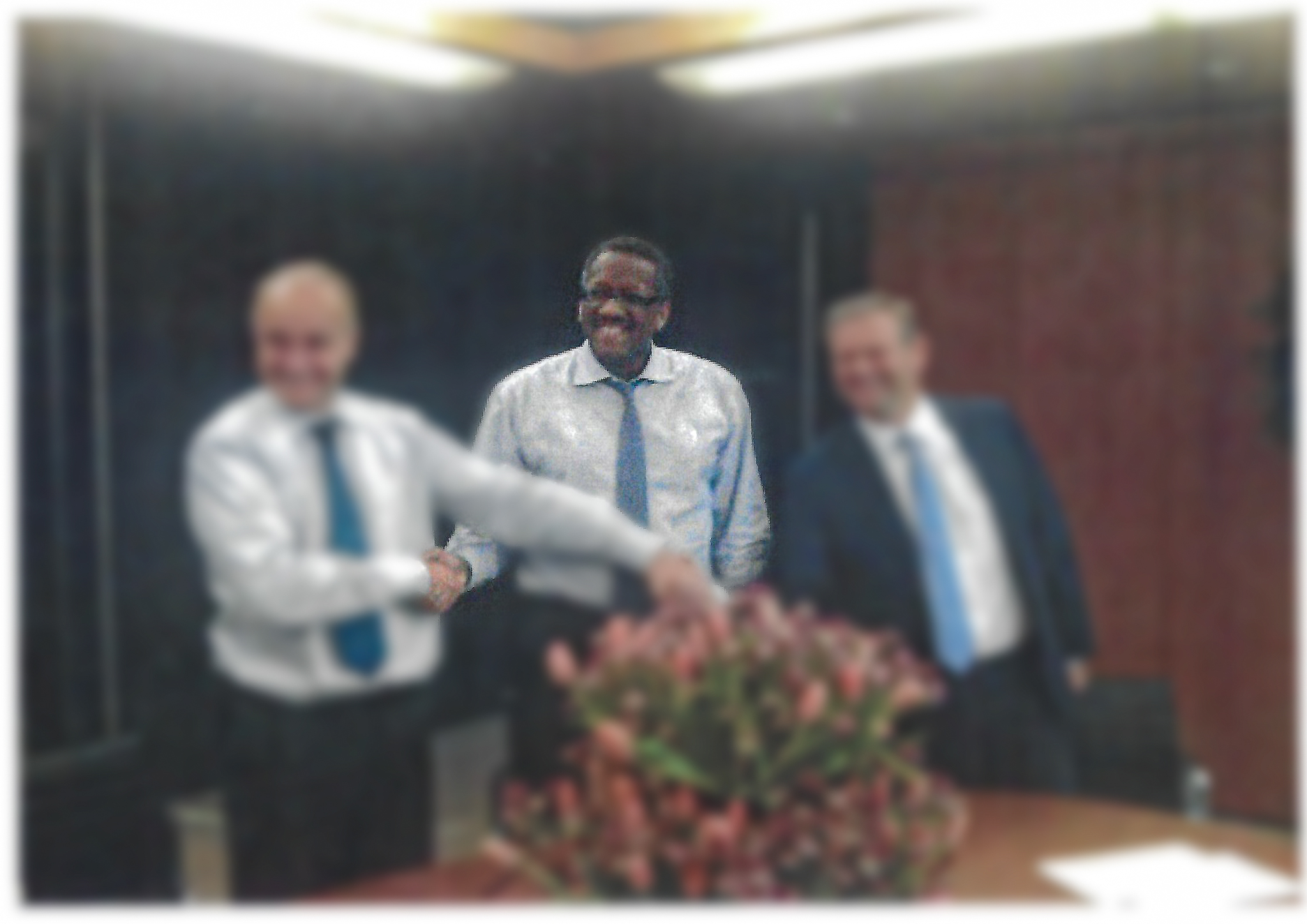 Patrick Franchinard during a business meeting with colleagues, observing a handshake between attendees.