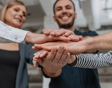 Team members stacking their hands together to represent collaboration, trust, and teamwork.